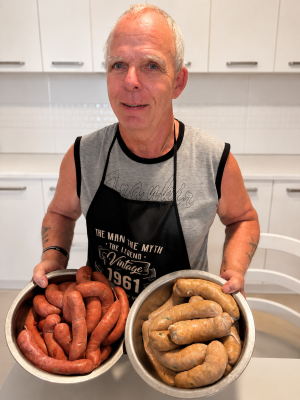 Dieter holding two bowls of freshly made homemade sausages in his kitchen